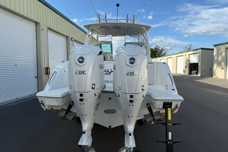 Slide: The Image of 2024 Pursuit DC 266 Dual Console boat with twin Yamaha 200 engines, parked near storage units. - 26