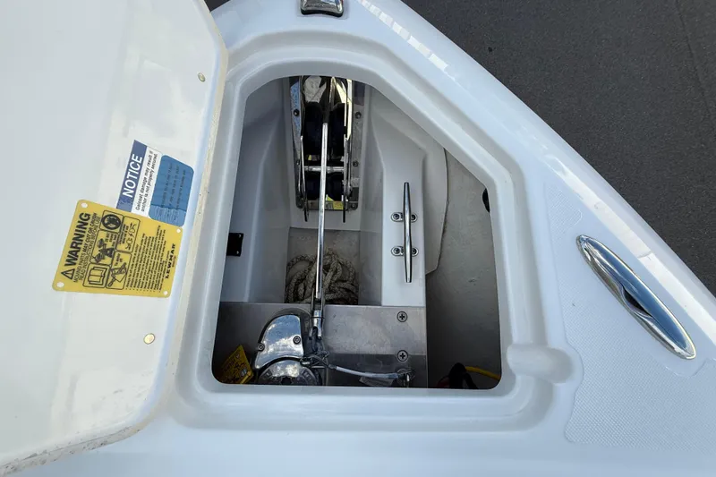 Slide: The Image of 2024 Pursuit DC 266 Dual Console anchor compartment with warning labels and equipment. - 30