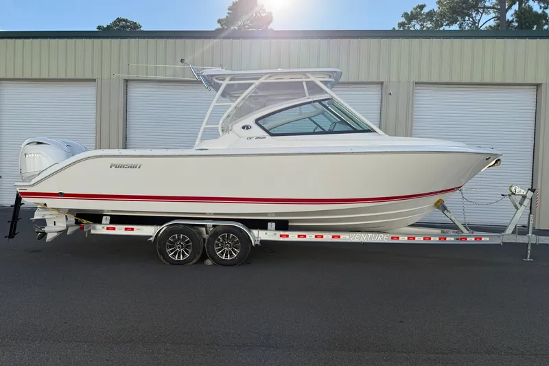 Slide: The Image of 2024 Pursuit DC 266 Dual Console boat on trailer, parked outside storage facility. - 5