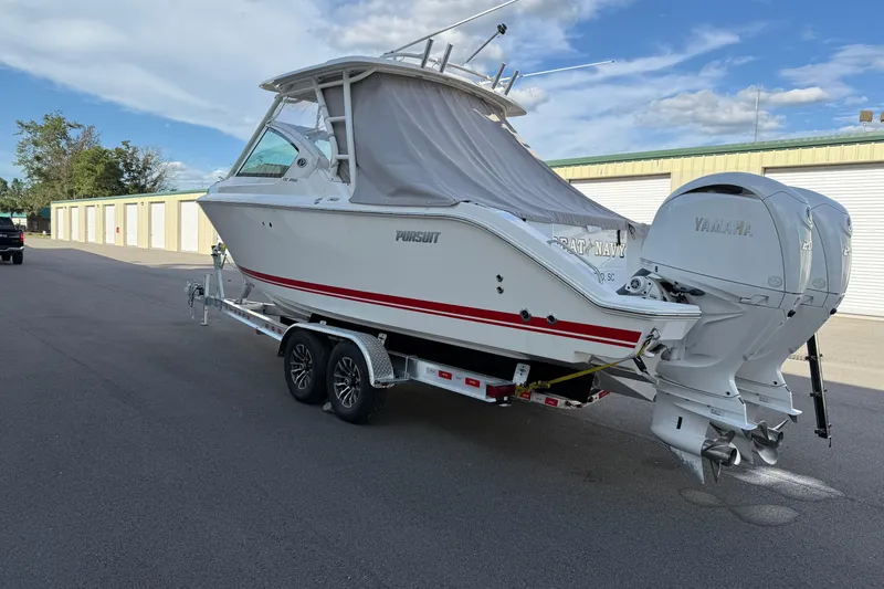 Slide: The Image of 2024 Pursuit DC 266 Dual Console boat on trailer with Yamaha engines, parked outdoors. - 50