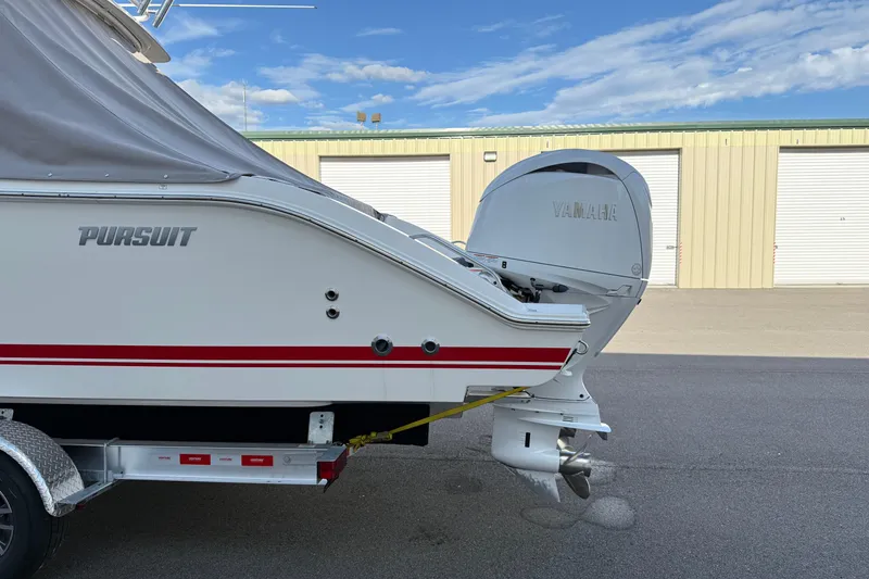 Slide: The Image of 2024 Pursuit DC 266 Dual Console boat with Yamaha outboard motor, parked near storage units. - 52