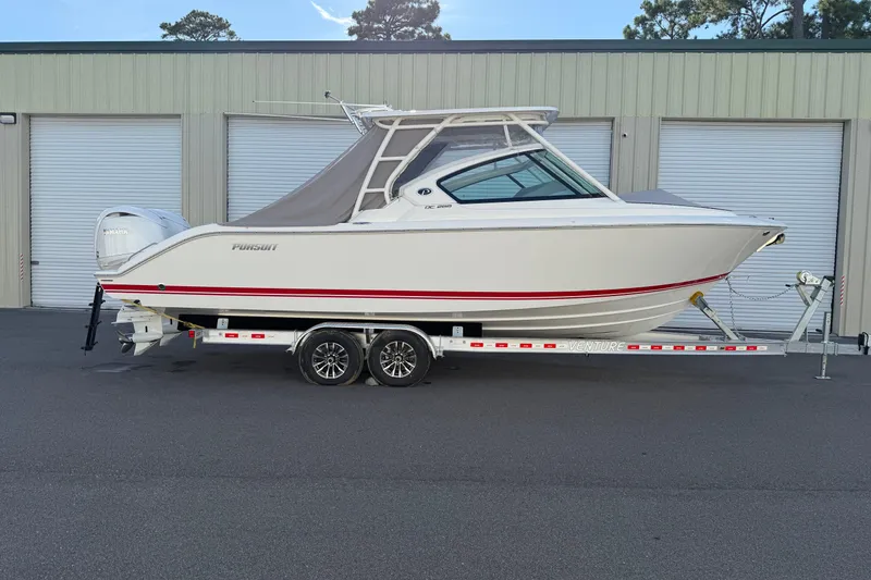 Slide: The Image of 2024 Pursuit DC 266 Dual Console boat on trailer, parked outside storage facility. - 54