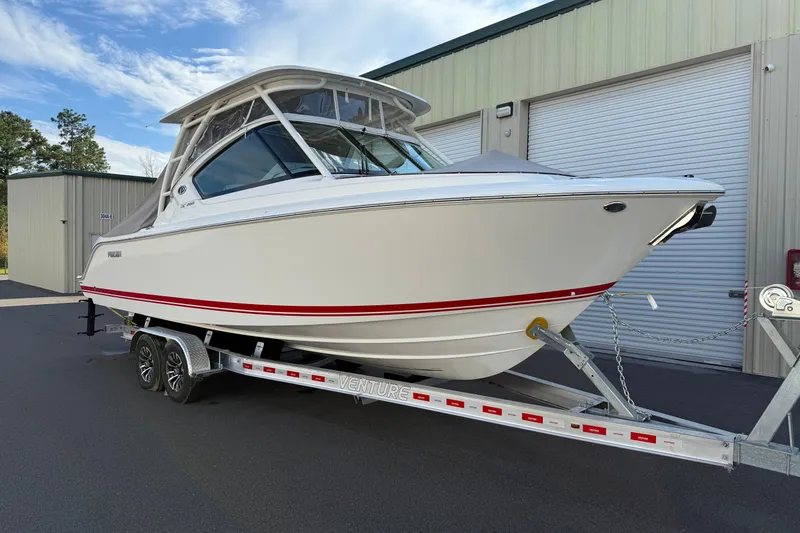 Slide: The Image of 2024 Pursuit DC 266 Dual Console boat on trailer, parked outside a warehouse. - 55