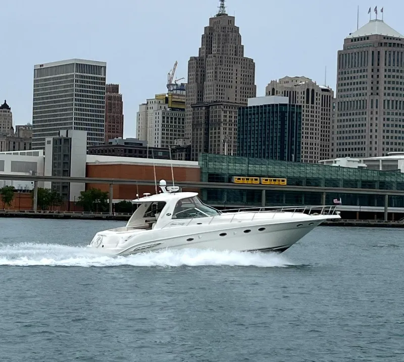 The Image of 2003 Sea Ray 460 Sundancer cruising on water with city skyline backdrop. - 0