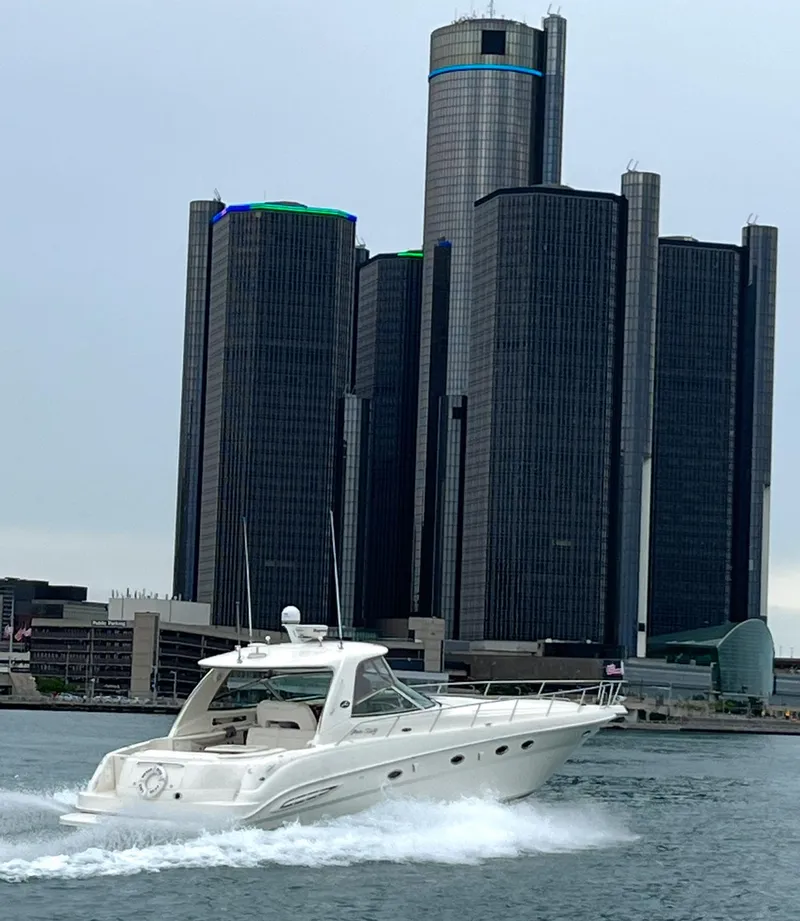 Slide: The Image of 2003 Sea Ray 460 Sundancer cruising near modern skyscrapers on a cloudy day. - 1