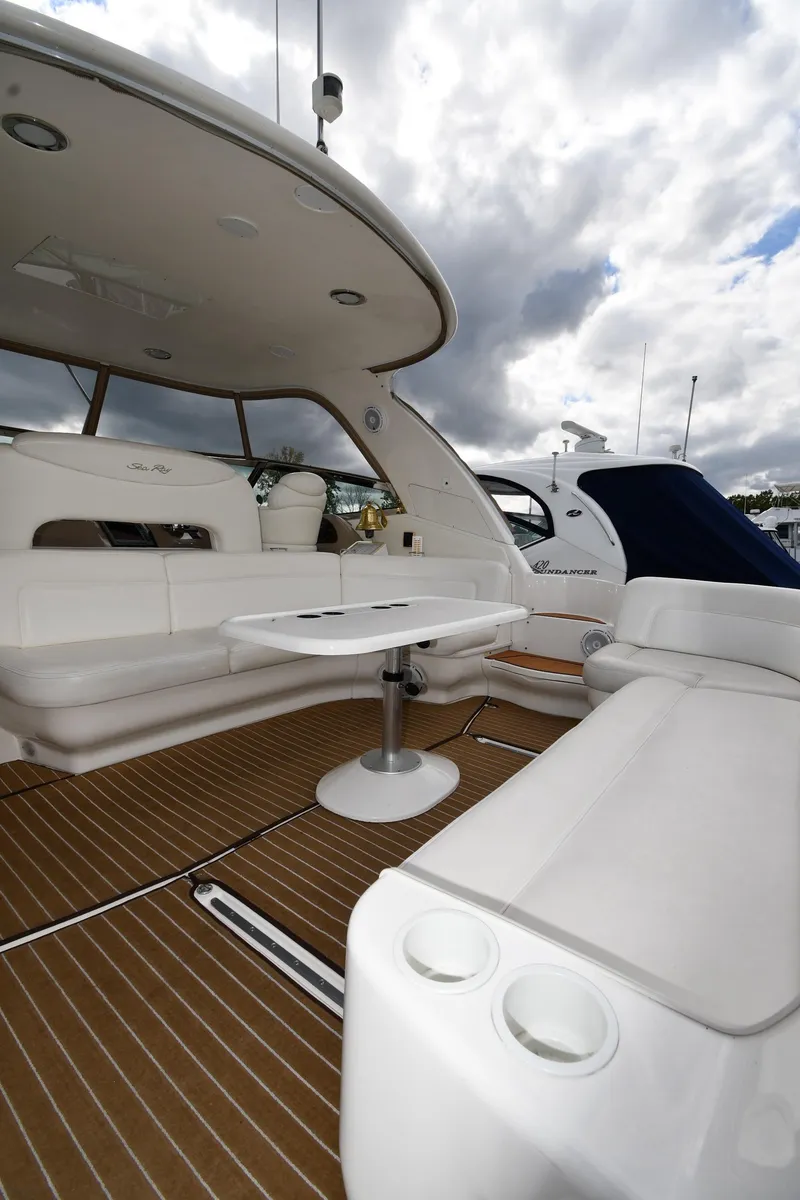 Slide: The Image of 2003 Sea Ray 460 Sundancer yacht interior with seating and table under cloudy sky. - 20