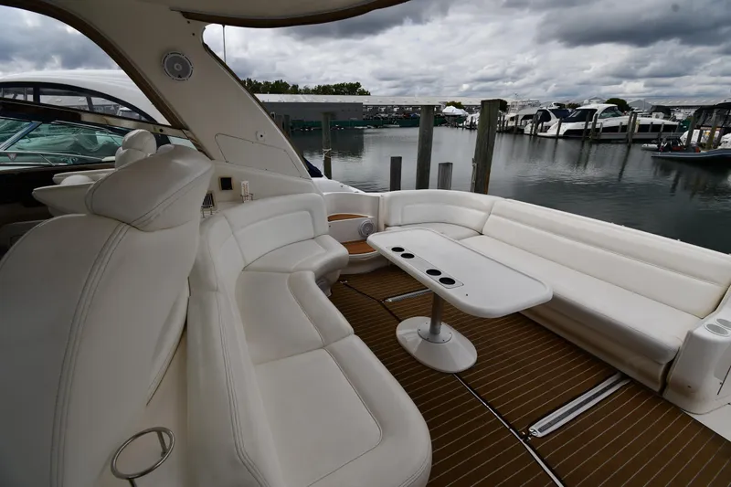 Slide: The Image of 2003 Sea Ray 460 Sundancer yacht interior with white seating and table, docked at marina. - 26