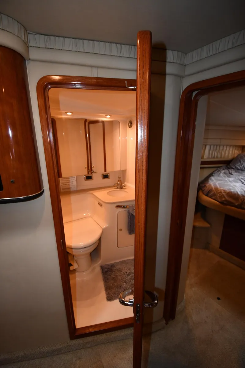 Slide: The Image of Interior of 2003 Sea Ray 460 Sundancer yacht, featuring a compact bathroom and cozy bedroom. - 42