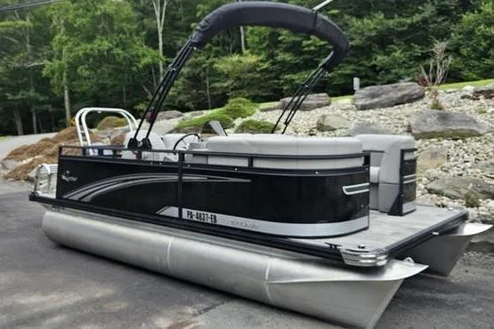 The Image of 2022 Apex Marine Qwest pontoon boat parked on a driveway with lush greenery background. - 0