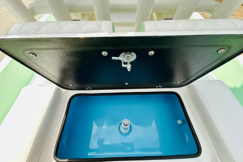 Slide: The Image of 2026 SCB R24 boat with open storage compartments and outboard motor in parking lot. - 9