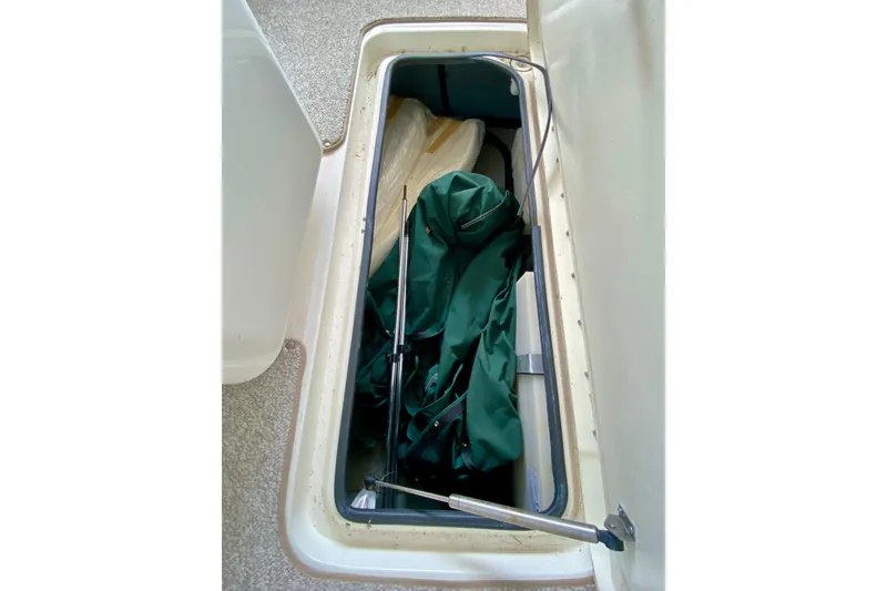 Slide: The Image of Open storage compartment on 2002 Sea Ray 290 SLX boat with green cover inside. - 27