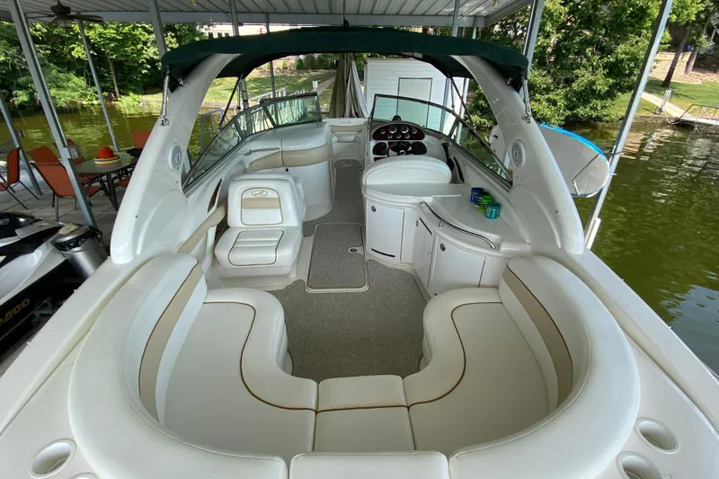 Slide: The Image of 2002 Sea Ray 290 SLX boat interior with spacious seating and helm, docked by the water. - 5