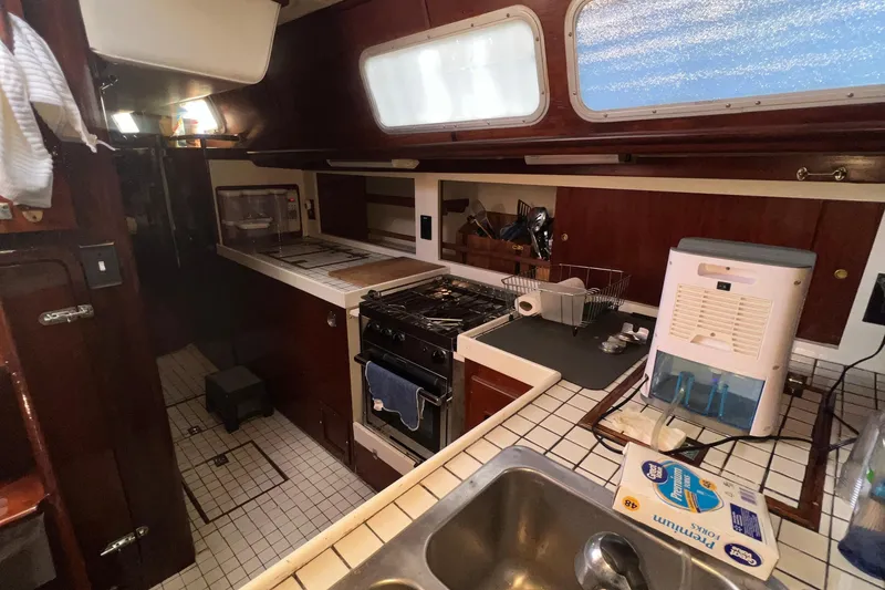 Slide: The Image of 1977 Gulfstar 50 yacht kitchen with stove, sink, and wooden cabinetry. - 22