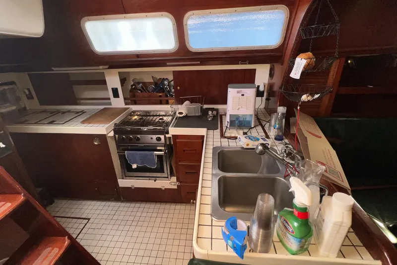 Slide: The Image of 1977 Gulfstar 50 yacht kitchen with stove, dual sinks, and wooden cabinetry. - 23