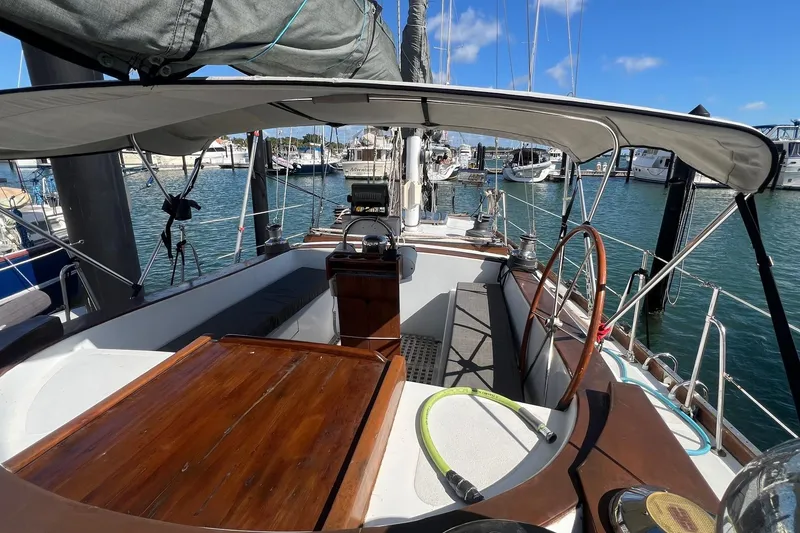 Slide: The Image of 1977 Gulfstar 50 sailboat cockpit with wooden accents, docked in a marina under clear blue skies. - 9