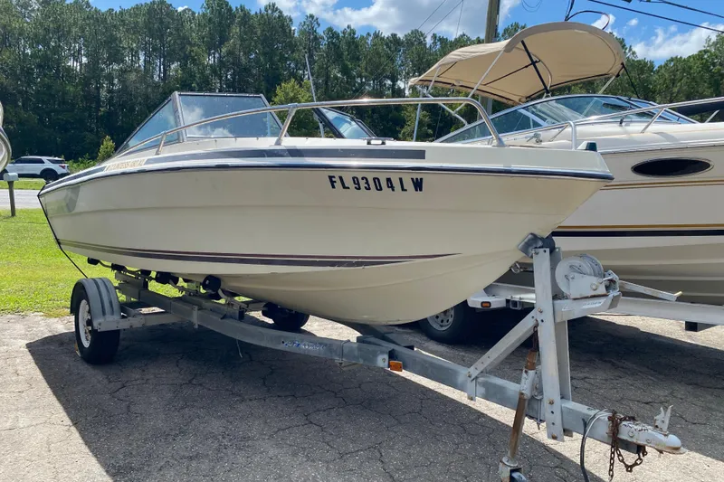 The Image of 1979 Regal 1800 Bowrider boat on trailer, parked outdoors under clear sky. - 1