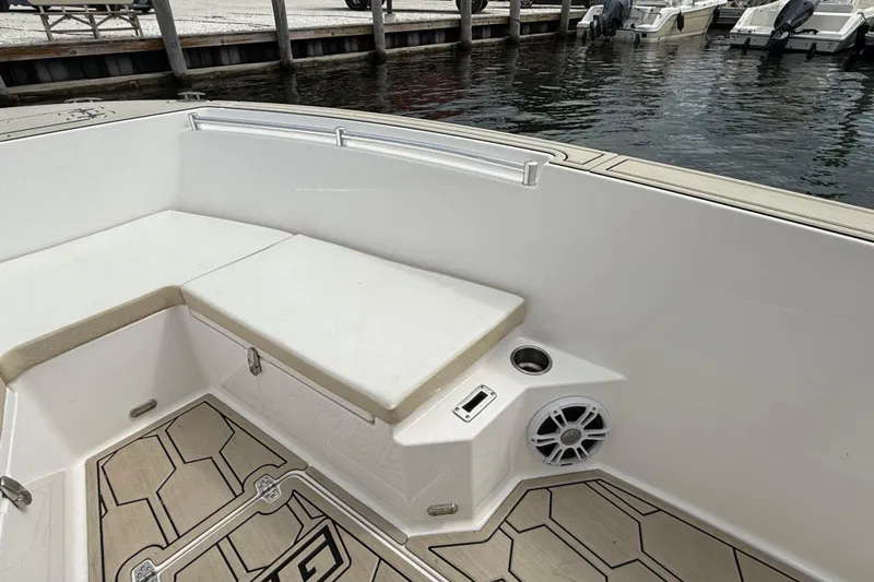 Slide: The Image of 2023 LFG 22 boat interior with cushioned seating and speaker, docked by the water. - 6