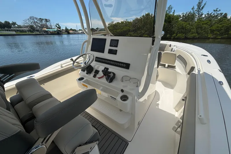 Slide: The Image of 2026 Key West 260 CC boat interior with modern helm and seating, docked by a scenic waterway. - 10