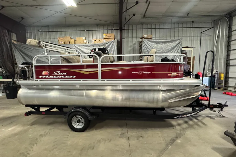 Slide: The Image of 2023 Sun Tracker Bass Buggy 16 XL Select pontoon boat in a garage setting. - 3