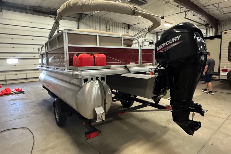 Slide: The Image of 2023 Sun Tracker Bass Buggy 16 XL Select pontoon boat with Mercury outboard motor in a garage. - 5