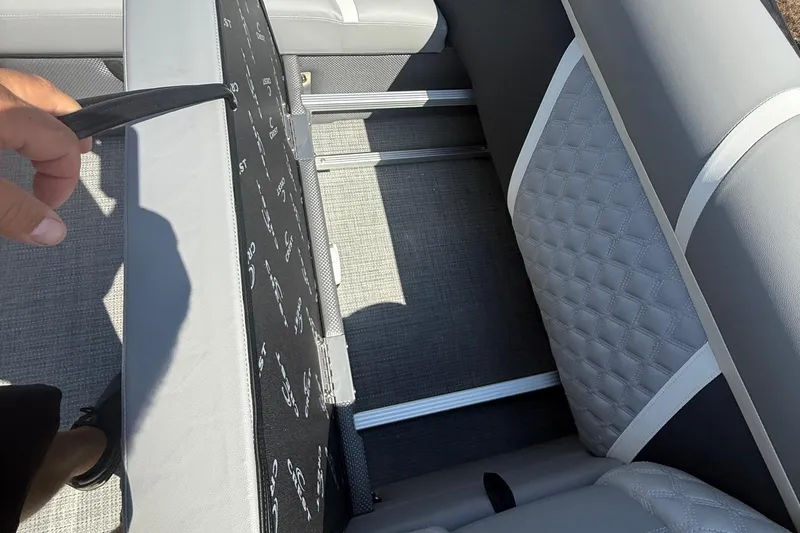 Slide: The Image of 2025 Crest Classic 200 boat seat storage compartment with gray upholstery and diamond stitching. - 23