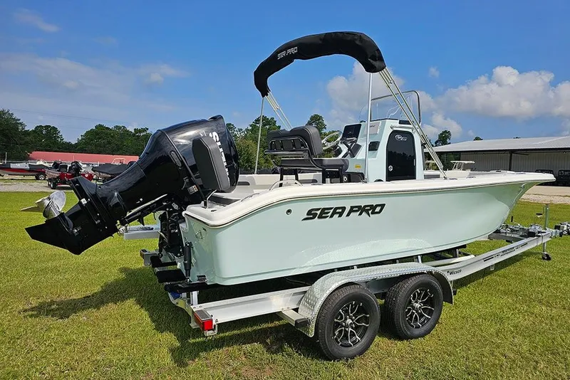 Slide: The Image of 2026 Sea Pro 202 Center Console boat on trailer, parked on grass under blue sky. - 2