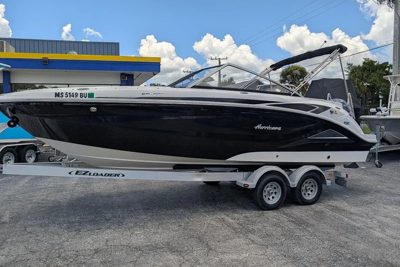 The Image of 2023 Hurricane SunDeck 235 OB boat on trailer, parked outdoors under blue sky. - 0