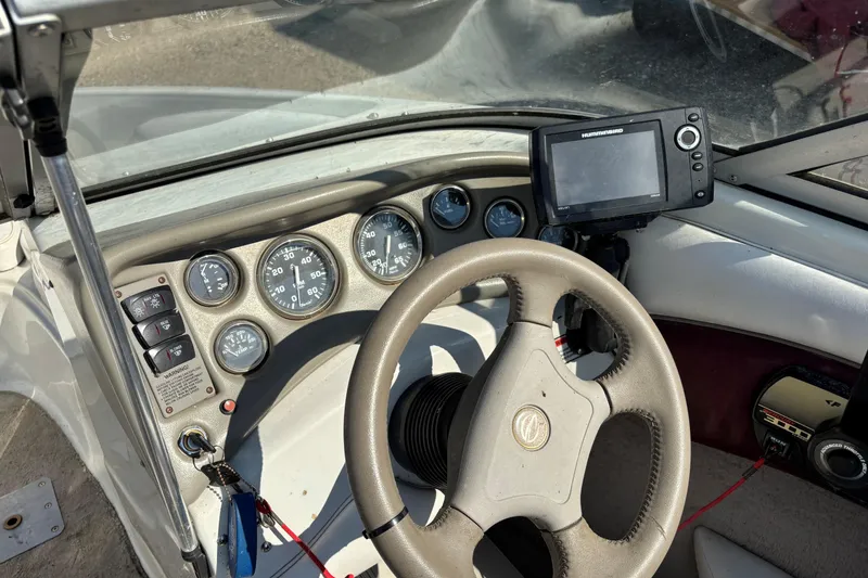 Slide: The Image of Crownline 180 BR 2000 boat dashboard with steering wheel, gauges, and navigation system. - 15