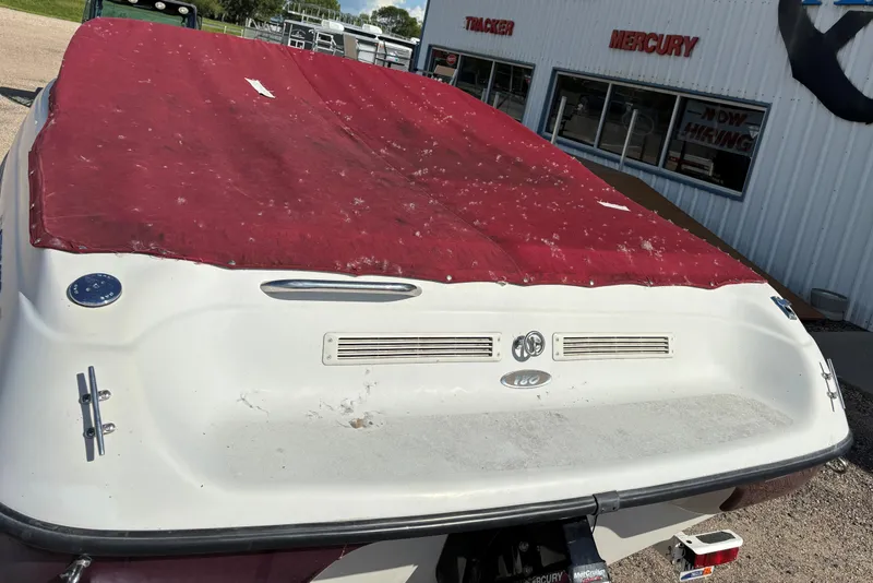 Slide: The Image of 2000 Crownline 180 BR boat with red cover, parked outside a dealership. - 19