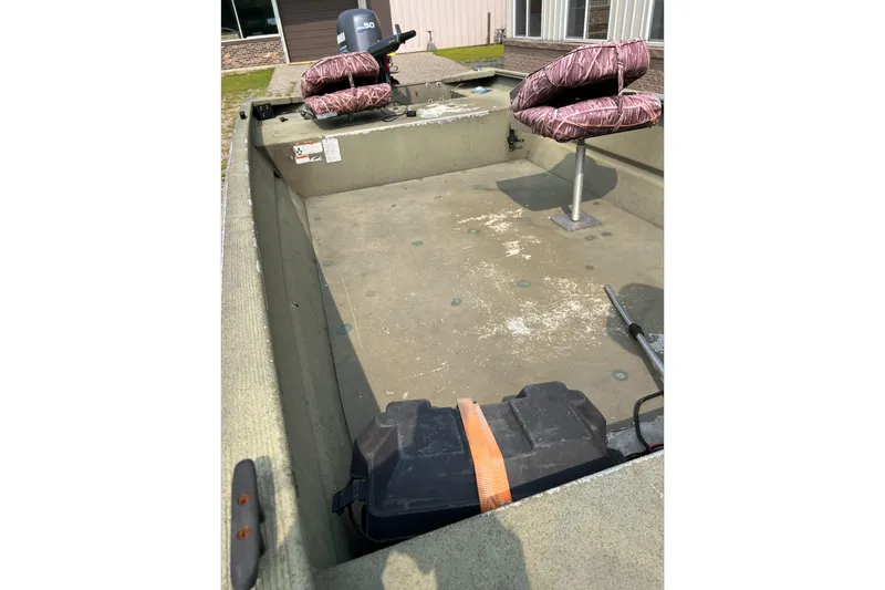 Slide: The Image of 2011 Tracker 1754 boat interior with camo seats and motor, parked outdoors. - 5