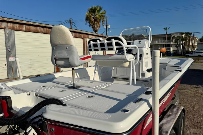 Slide: The Image of 2015 Epic 22 Sport Console boat with white seating and red exterior, parked outdoors. - 10