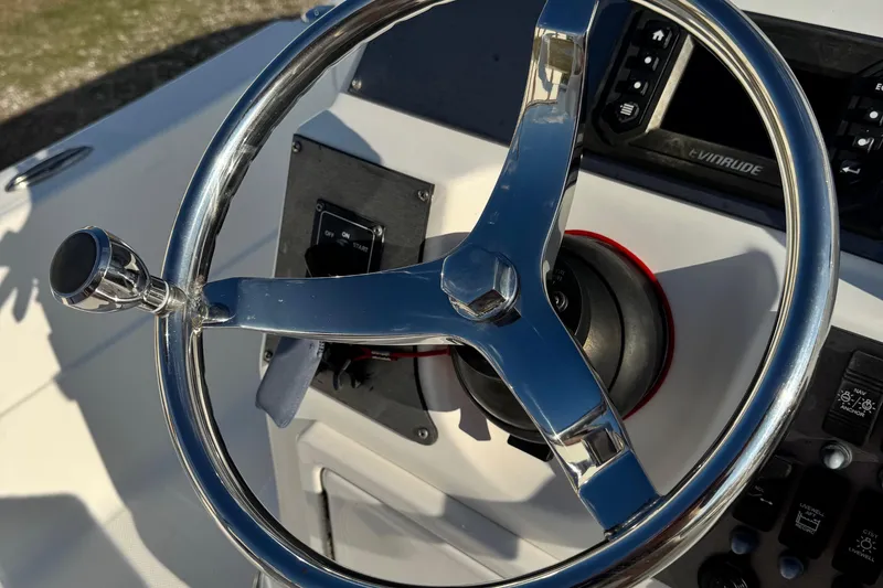 Slide: The Image of Steering wheel of a 2015 Epic 22 Sport Console boat, featuring chrome details. - 38