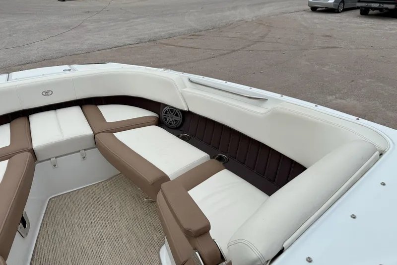 Slide: The Image of 2016 Cobalt 26SD boat interior with white and brown seating, parked on pavement. - 34