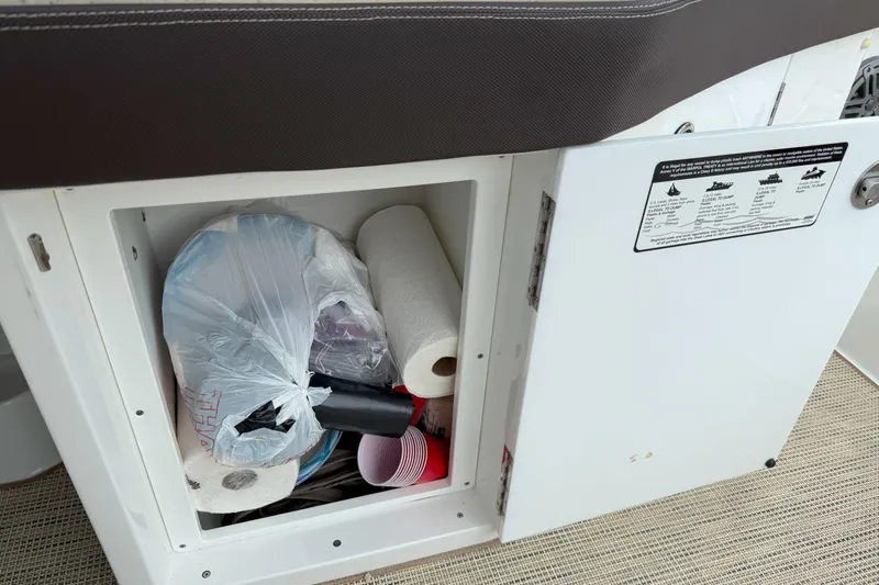 Slide: The Image of Open storage compartment in 2016 Cobalt 26SD boat with paper towels and plastic bags. - 46