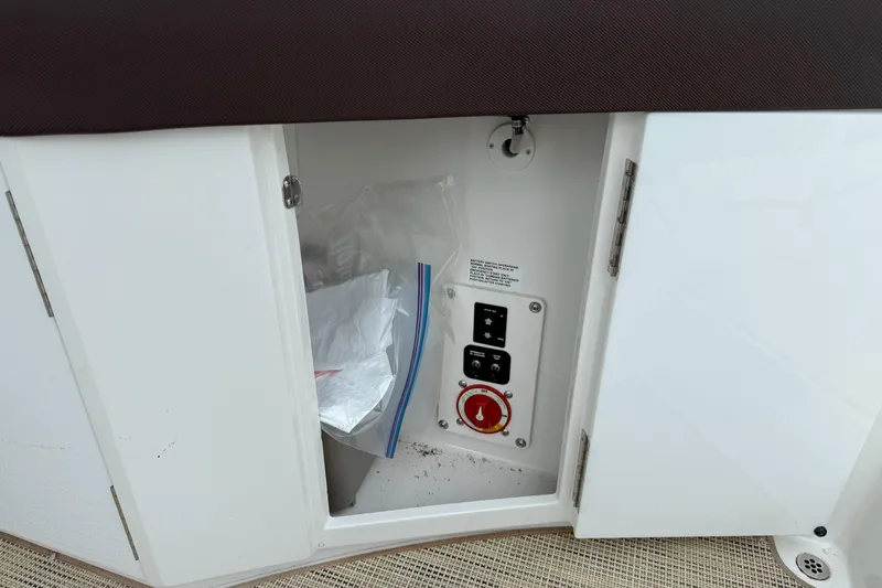 Slide: The Image of Open storage compartment on 2016 Cobalt 26SD boat, showing control panel and plastic bags. - 48