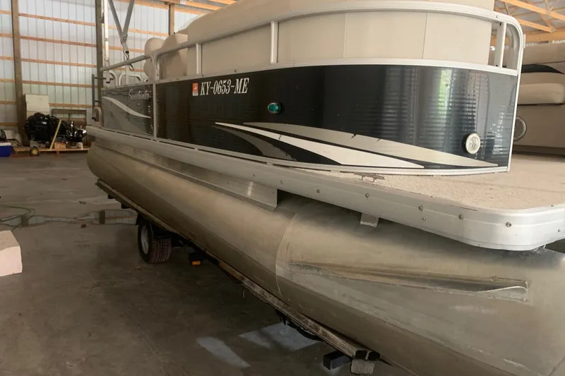 Slide: The Image of 2012 Sweetwater 2086 pontoon boat in storage, featuring a sleek black and white design. - 1