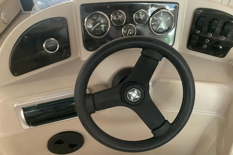 Slide: The Image of Steering wheel and dashboard of a 2012 Sweetwater 2086 boat, featuring gauges and controls. - 9