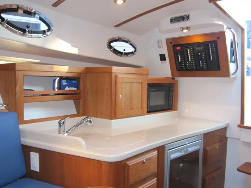 Slide: The Image of Interior of 2011 Back Cove 30 boat featuring a modern kitchen with wood cabinetry. - 10