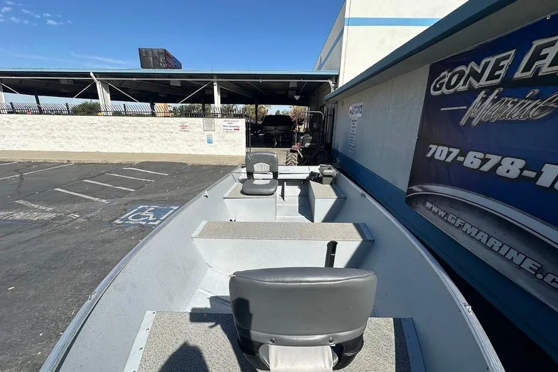 Slide: The Image of 2024 Lund WC-14 boat parked outside a marine dealership under clear blue skies. - 15