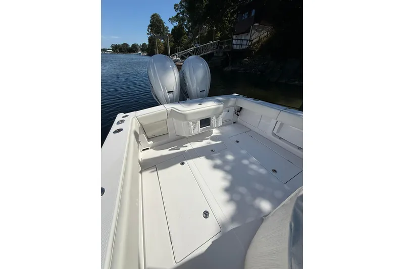 Slide: The Image of 2021 Jupiter 38 HFS boat deck with dual outboard motors, docked by a scenic waterfront. - 47