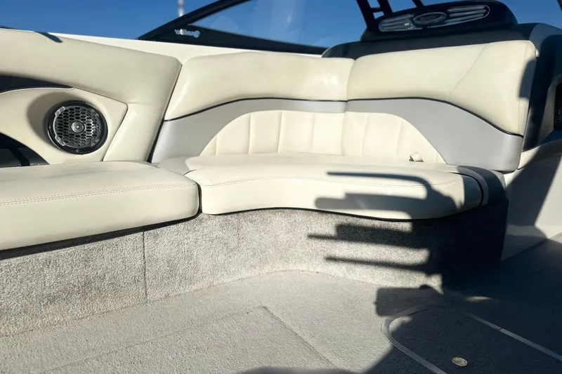 Slide: The Image of Interior seating of a 2008 Malibu Boats 23 LSV, featuring beige upholstery and speaker. - 6