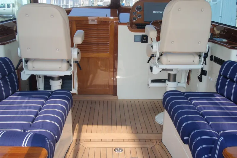 Slide: The Image of 2011 Hinckley Picnic Boat 37 MKIII interior with elegant wood finish and striped seating. - 4