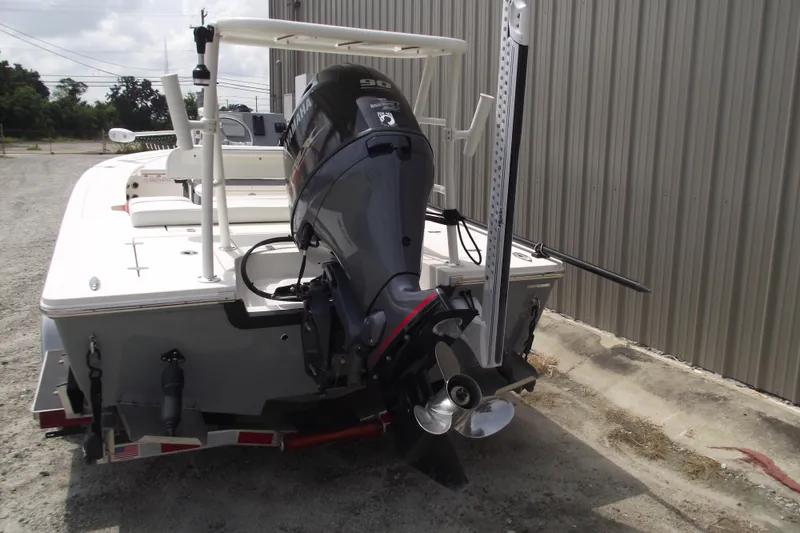 Slide: The Image of 2024 Hewes Redfisher 16 boat with Yamaha outboard motor, parked near a metal building. - 3
