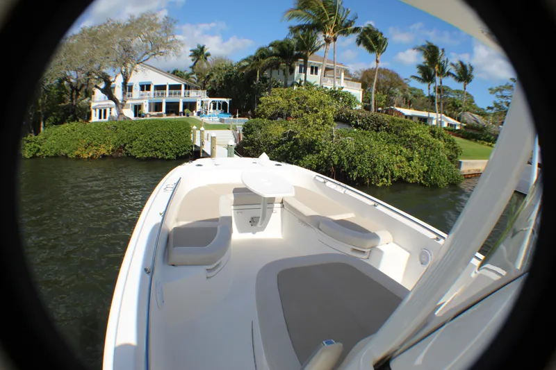 Slide: The Image of 2017 Boston Whaler 270 Dauntless boat docked near waterfront homes, surrounded by lush greenery. - 16