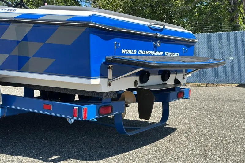 Slide: The Image of 2001 Centurion Elite Bowrider boat rear view, blue and white design, on a trailer. - 3