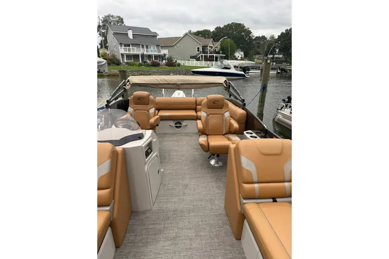 Slide: The Image of 2022 Crest Caribbean LX 230 SLS boat interior with tan seating, docked near waterfront homes. - 24