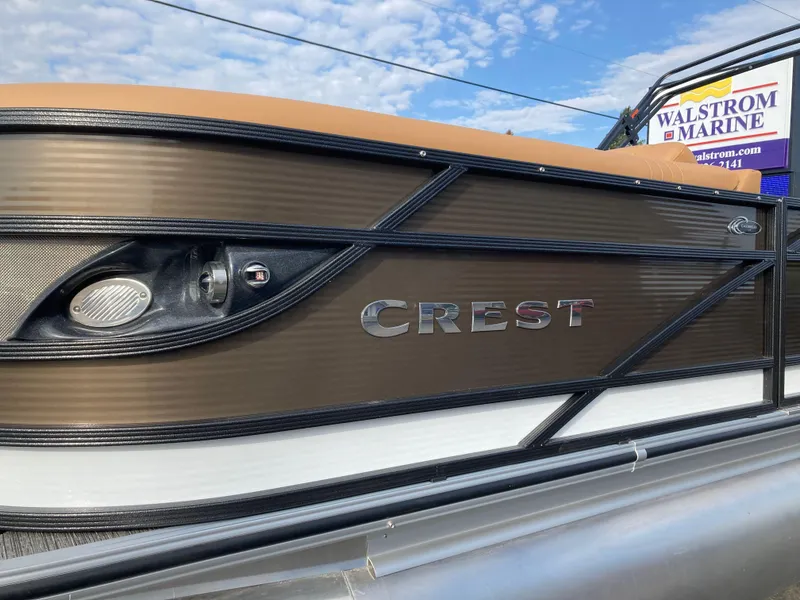 Slide: The Image of 2022 Crest Caribbean LX 230 SLS boat side view with logo and marine dealership sign. - 4