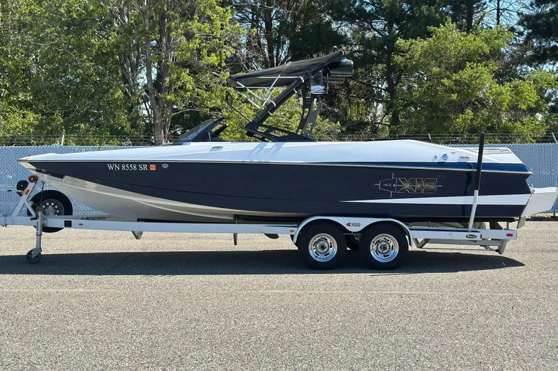 The Image of 2014 Axis A24 boat on trailer, parked outdoors with trees in the background. - 1
