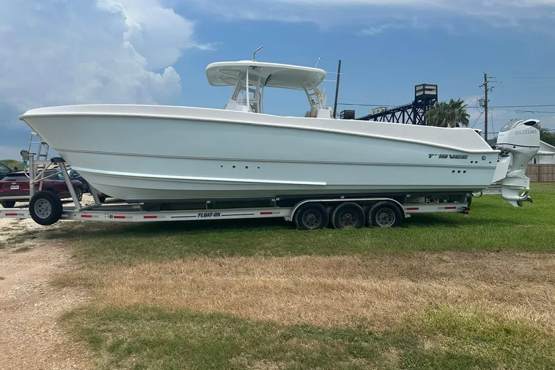 The Image of 2023 Twin Vee 340 GFX CC boat on trailer, parked on grass under cloudy sky. - 0
