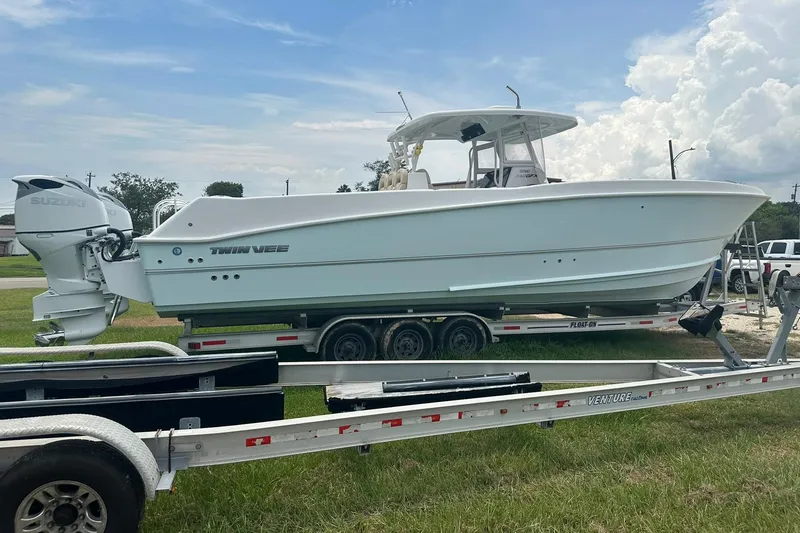 Slide: The Image of 2023 Twin Vee 340 GFX CC boat on trailer, featuring Suzuki outboard motor. - 13